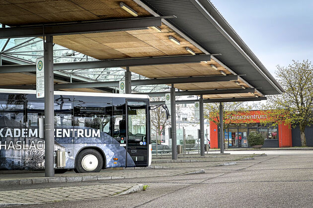 Bus bedruckt mit Werbung tagsüber in einer Bushaltestelle